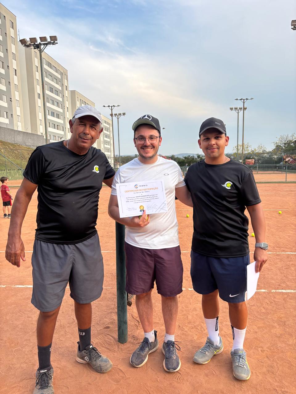 Aluno recebendo certificado ao lado dos treinadores da C-Tennis